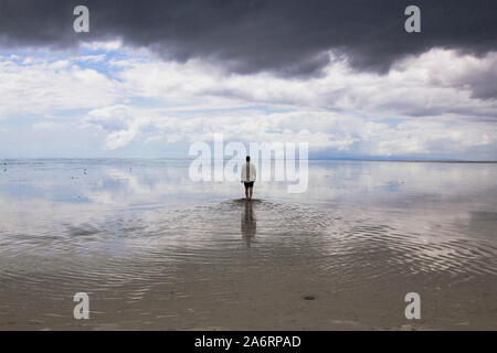 Uomo che cammina sulle acque cristalline specchio nell isola vergine Filippine Foto Stock