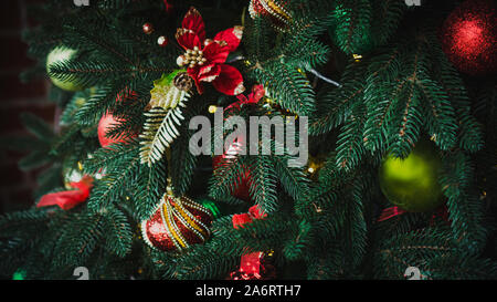 Nuovo Anno di rosso e verde sfere lucido appeso su un ramo di abete. Luci e ghirlande. Natale e felice anno nuovo concetto, vacanze invernali composizioni di luce Foto Stock