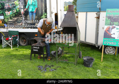 Un fabbro o da maniscalco Arraslea shires messa a ferro di cavallo su un'incudine, Chatsworth gioco o Country Fair, la Chatsworth House, Derbyshire, England, Regno Unito Foto Stock