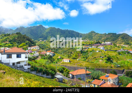 Bel villaggio Porto da Cruz in Isola di Madeira, Portogallo. Una piccola città circondata da verdi colline e foreste. Gli edifici rurali su una collina. Area remota, portoghese paesaggi. Destinazione turistica. Foto Stock
