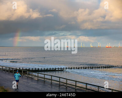 Aberdeen Beach, Aberdeen, Scozia, Regno Unito, 28 ottobre 2019. Regno Unito Meteo: Sole e docce in città causano un arcobaleno luminoso al tramonto sul Mare del Nord con la fattoria del vento nella baia di Aberdeen con un uomo che fa jogging sulla spianata Foto Stock