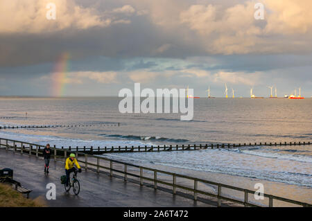 Spiaggia di Aberdeen, Aberdeen Scotland, Regno Unito, 28 ottobre 2019. Regno Unito: Meteo Sole e docce nella città causa un brillante arcobaleno al tramonto sul mare del nord guarda verso la fattoria eolica nella baia di Aberdeen con un ciclista sulla spianata Foto Stock