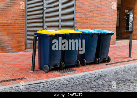 Varie immondizia di plastica contenitori con coperchi colorati per rispettosi dell'ambiente la cernita dei rifiuti o per il riciclaggio con piena di sacchetti di plastica per i rifiuti Foto Stock