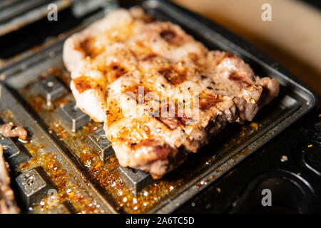 Barbecue di maiale è fritto su elettricità e servito al tavolo per festeggiare e mangiare cibo con carne fresca Foto Stock