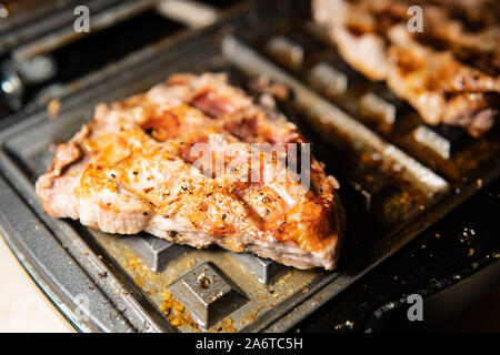 Cuciniamo al barbecue della casa, serviamo il cibo, glisten carne alla griglia con il grasso, cuociamo per il tavolo di festa, maiale arrosto Foto Stock