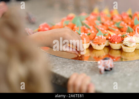 Il bambino sceglie una coloratissima torta in miniatura a una festa per i bambini Foto Stock