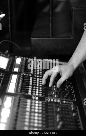 Il tecnico del suono al lavoro dietro una console di mixaggio in un concerto Foto Stock