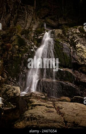 Autunno lunga esposizione del Creek e nero (grande) Stolpich cascate in Jizera Mountain. L'acqua cade in un profondo canyon di foresta piena di pietre di granito Foto Stock