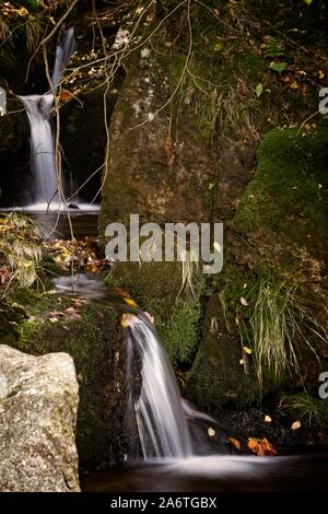 Autunno lunga esposizione del Creek e nero (grande) Stolpich cascate in Jizera Mountain. L'acqua cade in un profondo canyon di foresta piena di pietre di granito Foto Stock