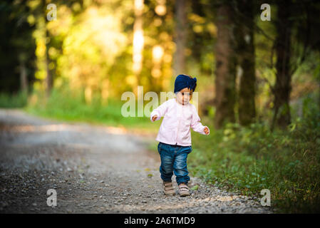 Ritratto di 2 anni bambina nella foresta a piedi da se stessa. Che non vogliono seguire i genitori. Foto Stock