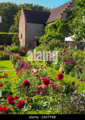 Chenies Manor Sunken giardino guardando verso il Padiglione edificio.Prato pathways e terrazzamenti aiuole piene di dalie su una bella serata. Foto Stock