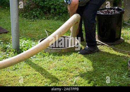 Vasca settica: La rimozione dei fanghi di depurazione e la pulizia di una vasca settica domestica nel giardino di una casa rurale francese Foto Stock