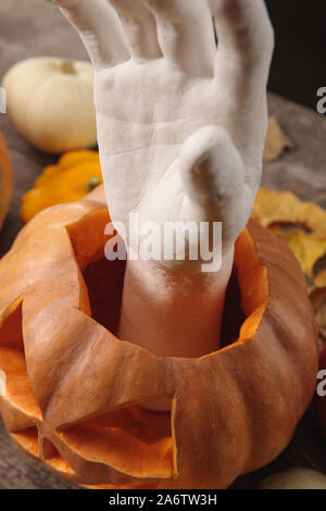 Decorativo in mano intagliato zucca di Halloween su legno tavolo rustico Foto Stock
