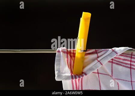 Un opacizzato asciugatutto appeso su uno stendibiancheria con una plastica clothespin davanti a uno sfondo scuro con casella di testo Foto Stock