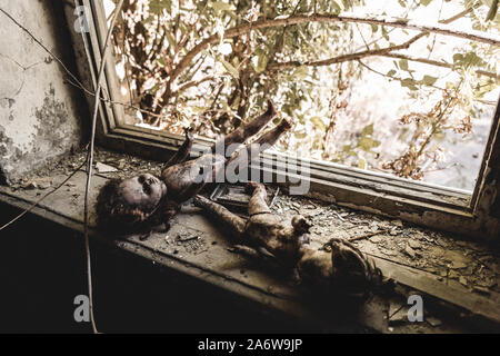 Messa a fuoco selettiva di paura e di bruciato baby dolls vicino alla finestra, post concetto apocalittico Foto Stock