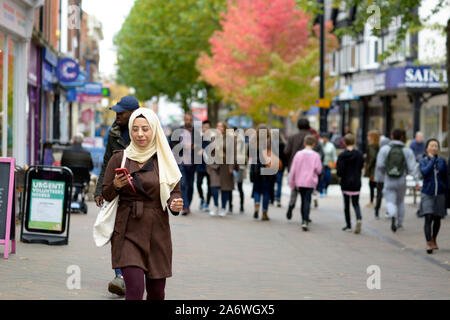 Donna musulmana, passeggiate, guardando il telefono cellulare Foto Stock