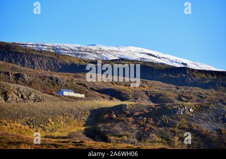 Distretto Hróarstunga, Islanda. Una casa immersa nelle montagne sopra Unaos ("l'estuario del Uni'). Panorami bellissimi abbondano nella zona. Foto Stock