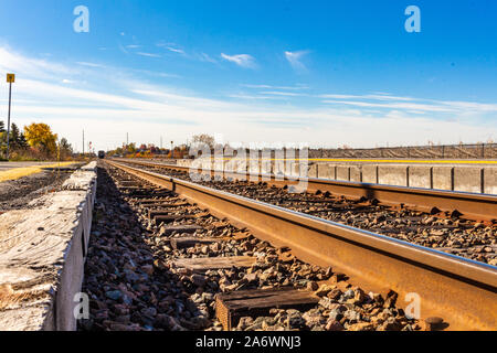 Su un perlopiù limpida giornata, fine auto passeggeri del treno può essere visto nel lontano orizzonte si allontana. I binari ferroviari vengono visualizzati a basso avanti e indietro Foto Stock