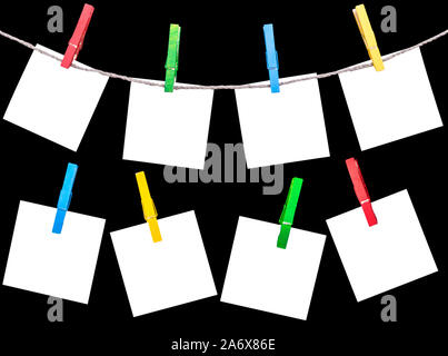 Blank white paper elenca imperniati con clothespins sulla corda isolato su sfondo nero. Vuoto bianco le schede di carta appeso con perni di vestiti con fune su b Foto Stock