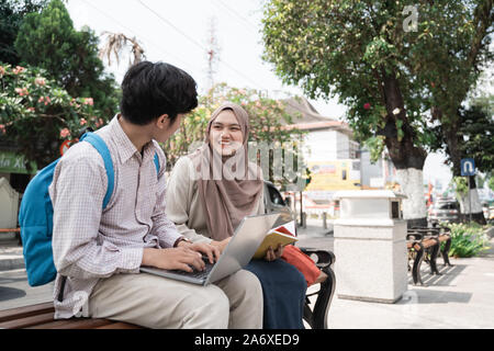 Due studenti adolescenti holding laptop e prenota quando chiacchierare insieme Foto Stock