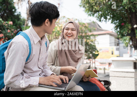 Due studenti adolescenti holding laptop e prenota quando chiacchierare insieme Foto Stock