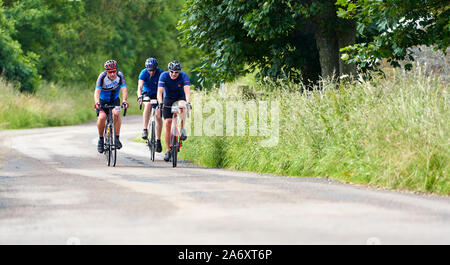 ROTHBURY, NEWCASTLE UPON TYNE, Regno Unito - Luglio 06, 2019: Tre ciclisti su strada di un paese a ciclone gara evento da Newcastle a Northumberlan Foto Stock