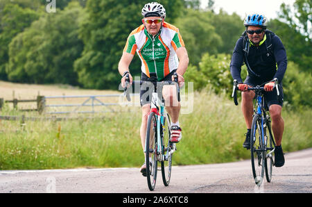 ROTHBURY, NEWCASTLE UPON TYNE, Regno Unito - Luglio 06, 2019: due senior ciclisti a cavallo lungo un vicolo del paese a ciclone gara evento da Newcastle t Foto Stock