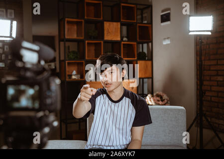 Asian giovane blogger vlog di registrazione parlando alla fotocamera Foto Stock