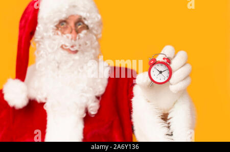 Sfocato Santa tenendo sveglia in mano a Orange Foto Stock