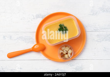 Purea di zuppa in scatola di plastica su plastica piastra arancione Foto Stock