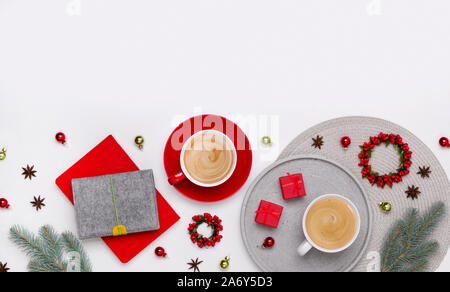 Ornamenti, Abete rami due tazze di caffè e rosso confezioni regalo su sfondo bianco Foto Stock