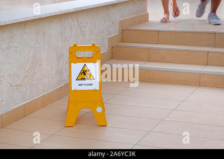 Cartello giallo avvertimento su pavimento bagnato. Iscrizione