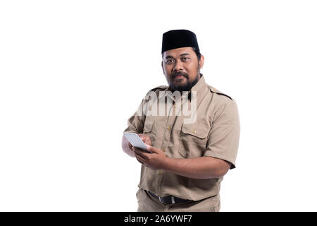 Lavoratore con uniforme marrone indonesia sorridente usando il telefono Foto Stock
