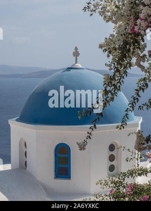 Una vista ravvicinata della mitica cupola blu chiesa cappella il tetto con il crocifisso trasversale in alto mare con le montagne sullo sfondo Oia Santorini Foto Stock