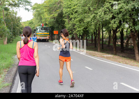 Donne jogging sulla via in posizione di stazionamento mentre si ascolta la musica sul telefono cellulare. Foto Stock