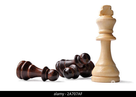 Luce di legno colorato re pezzo degli scacchi verticale circondata da opposizione pegni giacente sul loro lato in un gioco di strategia su bianco Foto Stock