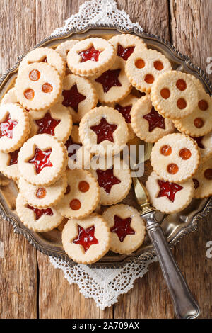 Tradizionale austriaca con biscotti di Natale - Linzer biscotti riempito con fragola rossa e confettura di albicocca vicino sul tavolo. Verticale in alto vista da abov Foto Stock