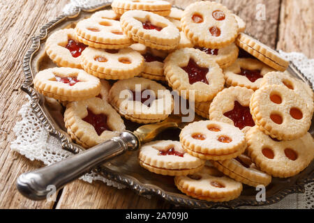 Tradizionale austriaca con biscotti di Natale - Linzer biscotti riempito con fragola rossa e confettura di albicocca vicino sul tavolo. Posizione orizzontale Foto Stock