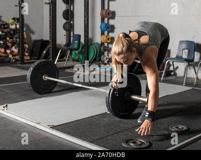Giovani femmine del peso di carico del sollevatore di pesi su heavy barbell in palestra. Foto Stock