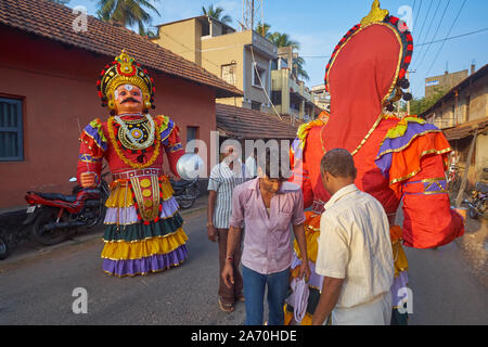 Durante un festival Balkrishna intorno al tempio di Udipi, Karnataka, India, guerriero gigante pupazzi con un uomo ogni nascosto all'interno di prendere parte a una processione Foto Stock