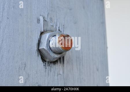 Rosso ruggine il bullone e il dado su un bianco parete in legno Foto Stock