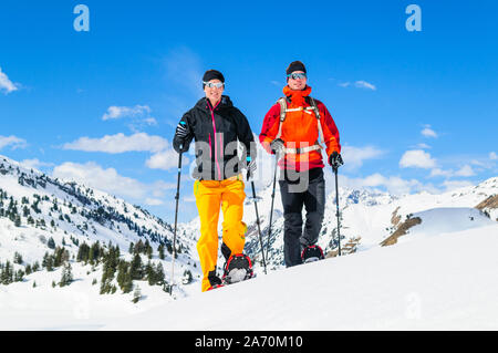 Coppia giovane escursionismo con le racchette da neve in una bella giornata nel tardo inverno Foto Stock