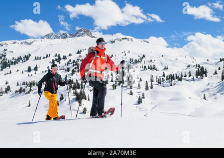 Coppia giovane escursionismo con le racchette da neve in una bella giornata nel tardo inverno Foto Stock