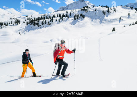 Coppia giovane escursionismo con le racchette da neve in una bella giornata nel tardo inverno Foto Stock