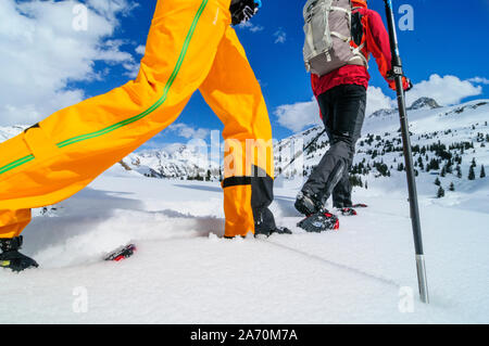 Coppia giovane escursionismo con le racchette da neve in una bella giornata nel tardo inverno Foto Stock