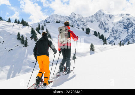 Coppia giovane escursionismo con le racchette da neve in una bella giornata nel tardo inverno Foto Stock