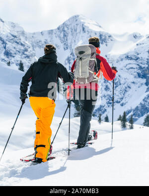 Coppia giovane escursionismo con le racchette da neve in una bella giornata nel tardo inverno Foto Stock