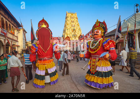 Durante un festival Balkrishna intorno al tempio di Udipi, Karnataka, India, guerriero gigante pupazzi con un uomo ogni nascosto all'interno di prendere parte a una processione Foto Stock