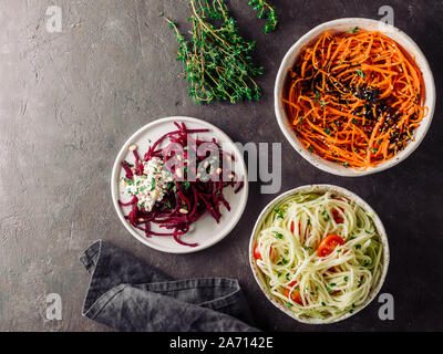 Idee e ricette per una sana insalata piccante - sesamo carota insalata di tagliatelle,materie barbabietola tagliatelle in montagna con la ricotta,zoodles di zucchine con insalata di pomodori.vari piatti vegetariani insalate pronte da mangiare.Top view.spazio di copia Foto Stock