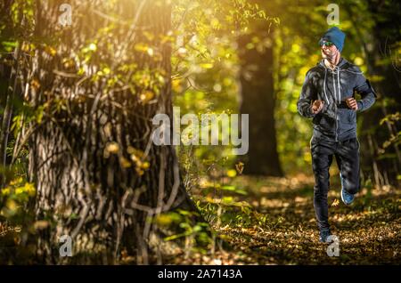 Pomeriggio Attività in esecuzione. Uomini caucasici nella sua 30s in esecuzione attraverso la spettacolare caduta della foresta di tempo. Foto Stock